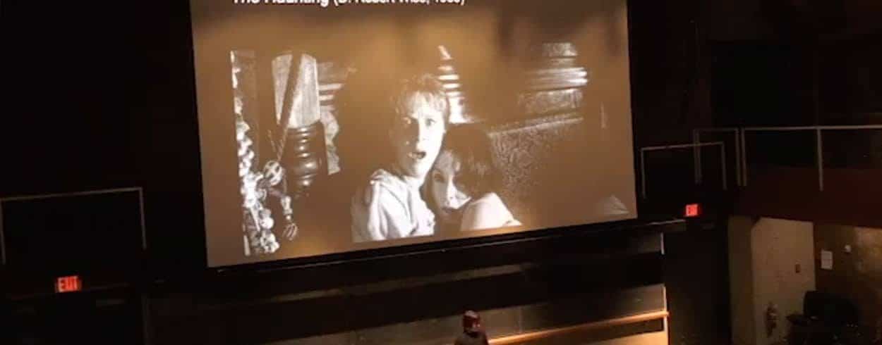 a projection of man and woman embracing in an auditorium at a movie showing.