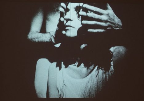 still from video of person behind someone, hands on either side of their face