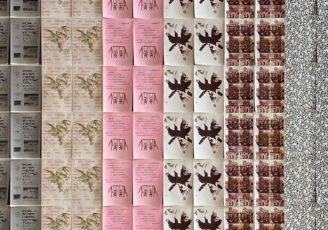 A wall is filled with a grid of posters hanging closely together; copies of 10 different posters are repeated to cover the wall